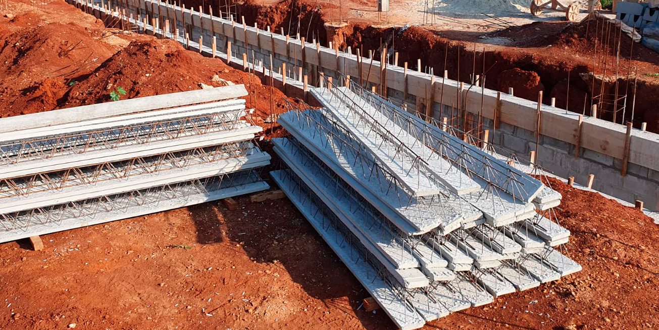 Trilhos de concreto treliçados empilhados em obra para montagem de lajes